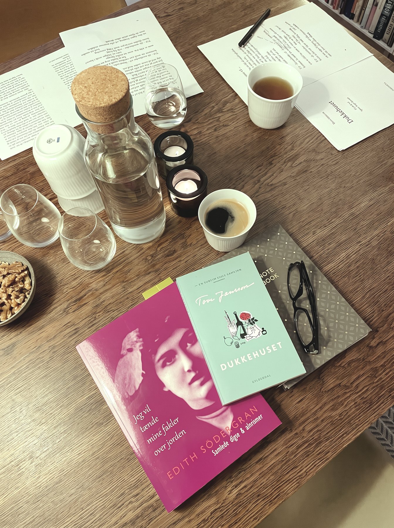 Bord med opslåe bøger, te-lys, kaffe og trykte digte på en litteraturklubaften