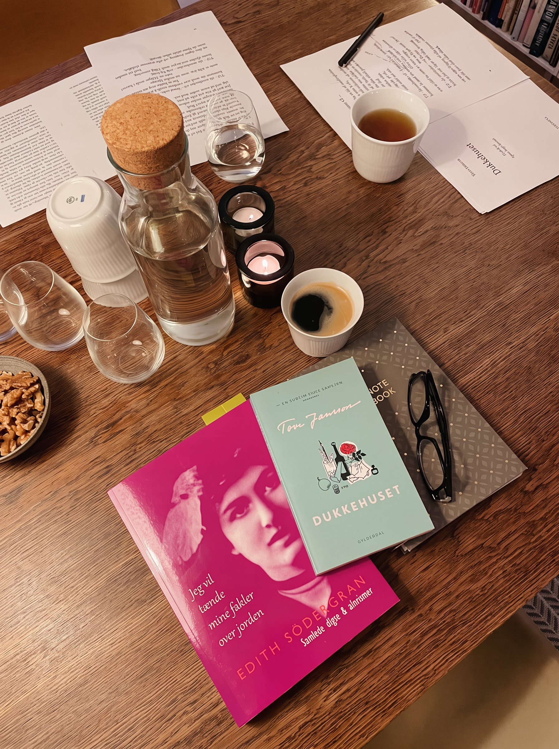 Bord med opslåe bøger, te-lys, kaffe og trykte digte på en litteraturklubaften